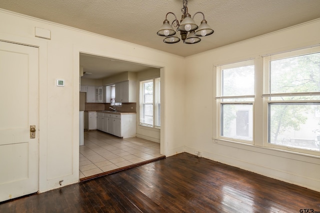 unfurnished dining area featuring a chandelier, plenty of natural light, light hardwood / wood-style flooring, and a textured ceiling