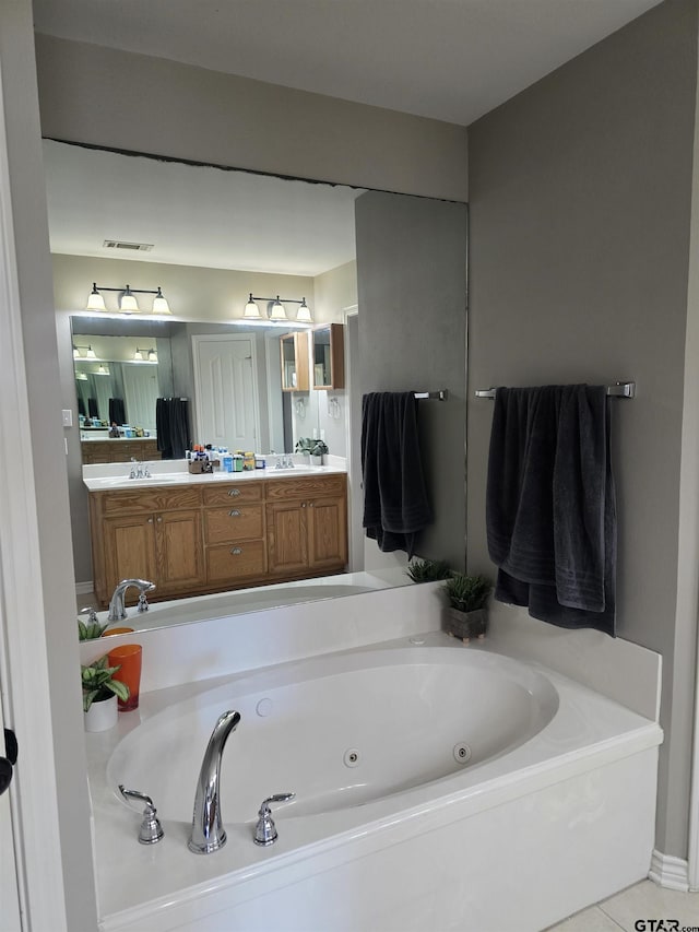 bathroom with tile patterned flooring, a jetted tub, and vanity