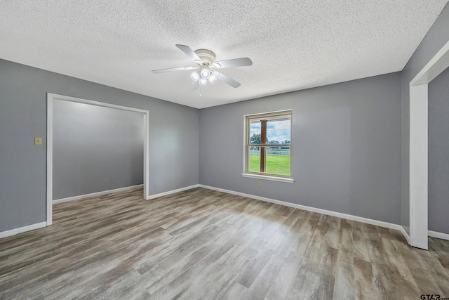 empty room with ceiling fan, a textured ceiling, and light wood-type flooring