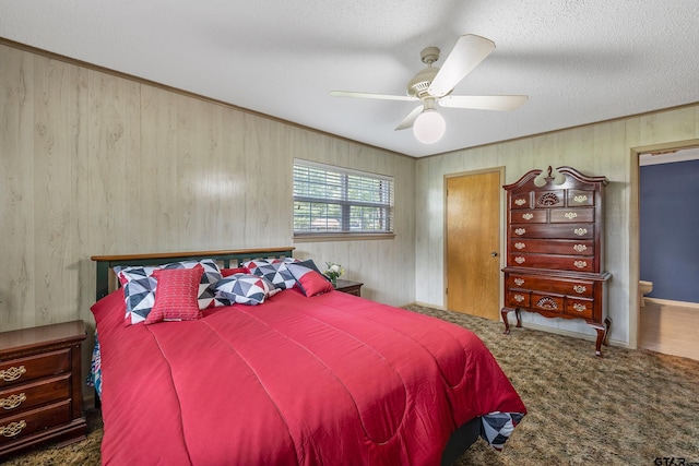 carpeted bedroom featuring a textured ceiling, ensuite bathroom, ceiling fan, and wooden walls