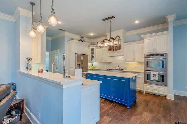 kitchen with appliances with stainless steel finishes, hanging light fixtures, blue cabinets, white cabinets, and dark hardwood / wood-style flooring