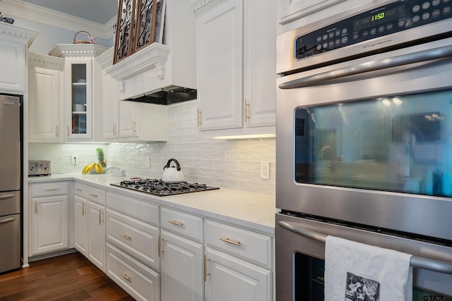 kitchen with white cabinetry, appliances with stainless steel finishes, ornamental molding, dark hardwood / wood-style floors, and backsplash