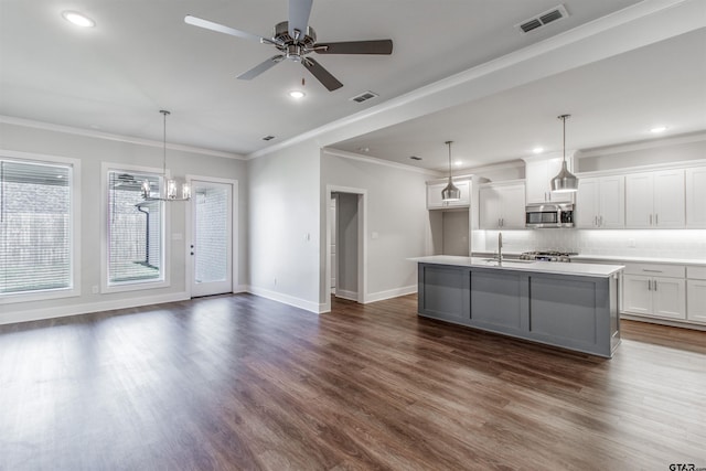 7013 Hillside Ave, Tyler, TX 75707 - kitchen featuring stainless steel microwave, crown molding, decorative backsplash, a ceiling fan, and dark wood finished floors