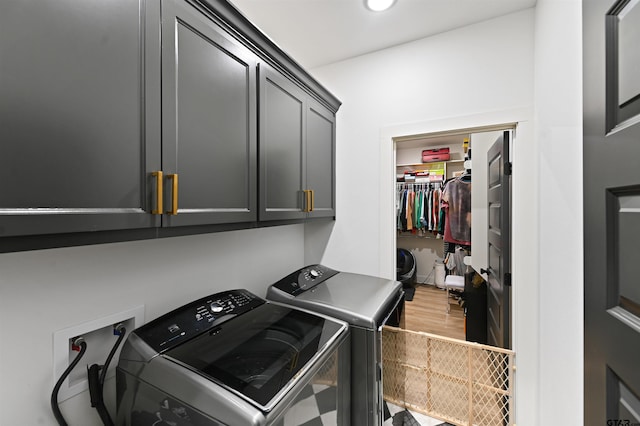 clothes washing area featuring hardwood / wood-style flooring, cabinets, and separate washer and dryer