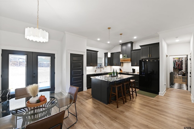 kitchen with pendant lighting, a center island, black fridge, light hardwood / wood-style flooring, and a breakfast bar area