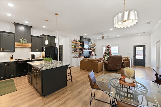 kitchen featuring pendant lighting, a center island, black appliances, and ceiling fan with notable chandelier