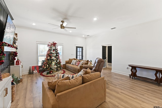 living room featuring ceiling fan, light hardwood / wood-style floors, crown molding, and a fireplace