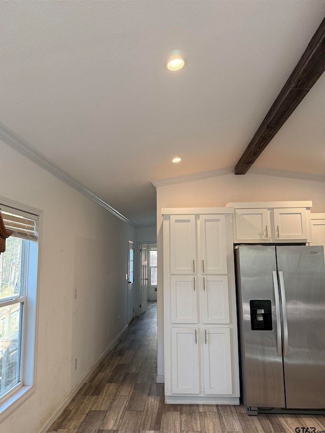 kitchen with stainless steel refrigerator with ice dispenser, dark wood-type flooring, crown molding, lofted ceiling with beams, and white cabinetry