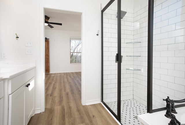 bathroom featuring a shower with door, vanity, wood-type flooring, and ceiling fan