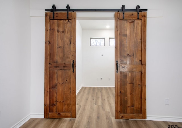 corridor with a barn door and light wood-type flooring