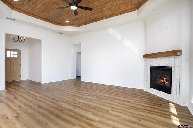 unfurnished living room with a tray ceiling, ceiling fan with notable chandelier, a fireplace, light hardwood / wood-style floors, and wood ceiling