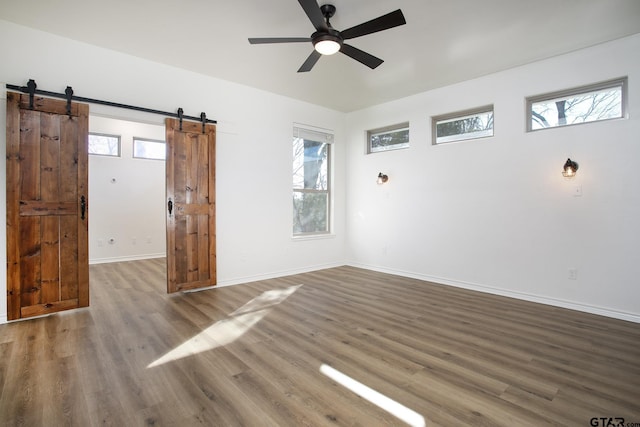 spare room featuring hardwood / wood-style flooring, a barn door, and ceiling fan