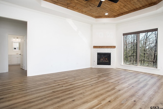 unfurnished living room featuring a tile fireplace, ceiling fan, a tray ceiling, wood-type flooring, and wooden ceiling