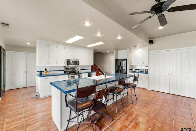 7016 Fm 3054, Malakoff, TX 75148 - kitchen featuring appliances with stainless steel finishes, a kitchen breakfast bar, light tile patterned floors, a sink, and white cabinetry