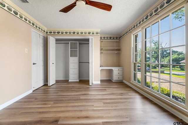 unfurnished bedroom featuring ceiling fan, wood-type flooring, a textured ceiling, and multiple windows