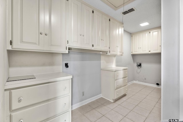 laundry room with electric dryer hookup, cabinets, hookup for a washing machine, a textured ceiling, and light tile patterned flooring