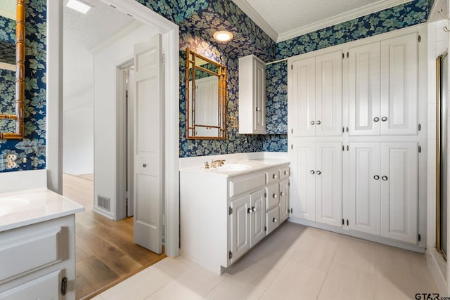 bathroom featuring crown molding, tile patterned flooring, vanity, and a textured ceiling