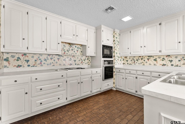 kitchen with a textured ceiling, white cabinetry, and black appliances