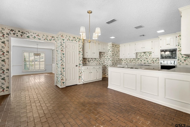 kitchen with pendant lighting, stainless steel oven, white cabinets, and black microwave