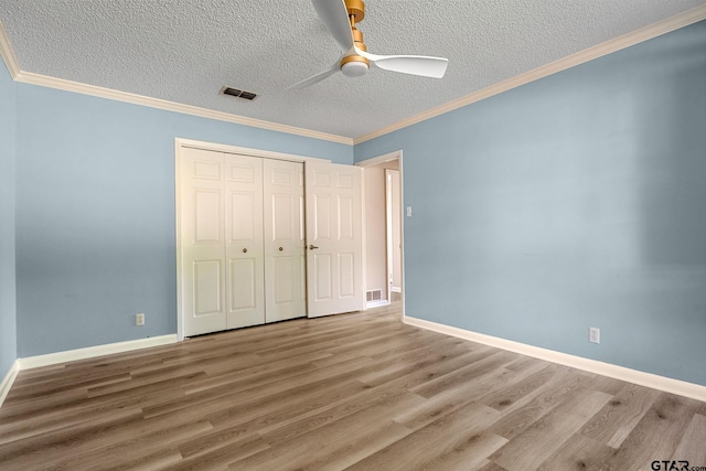 unfurnished bedroom with ornamental molding, a textured ceiling, ceiling fan, hardwood / wood-style flooring, and a closet