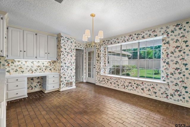 kitchen with a textured ceiling, white cabinetry, hanging light fixtures, and a notable chandelier