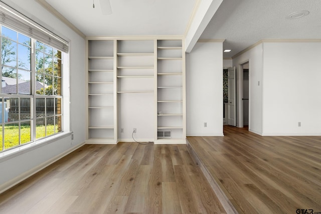 interior space featuring hardwood / wood-style floors, ornamental molding, a textured ceiling, and a wealth of natural light