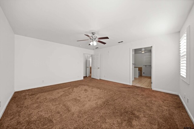 unfurnished bedroom with ceiling fan, ensuite bath, light carpet, and multiple windows