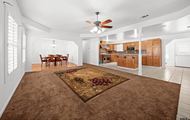 tiled living room with ceiling fan with notable chandelier