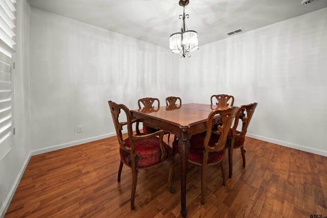 dining room with dark hardwood / wood-style floors and an inviting chandelier