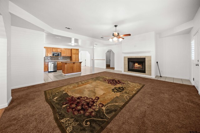 carpeted living room with ceiling fan and a fireplace