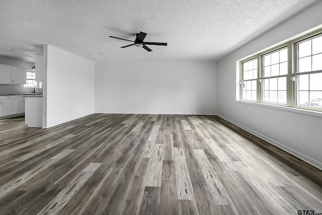 unfurnished living room with ceiling fan, plenty of natural light, sink, and hardwood / wood-style flooring