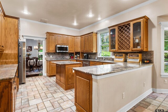 3631 River Oaks Ct, Tyler, TX 75707 - kitchen with appliances with stainless steel finishes, a peninsula, a sink, decorative backsplash, and brown cabinets