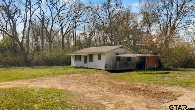 view of front of home featuring an outbuilding, driveway, and a front lawn