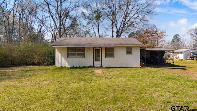 view of front facade featuring a carport, an outdoor structure, and a front lawn