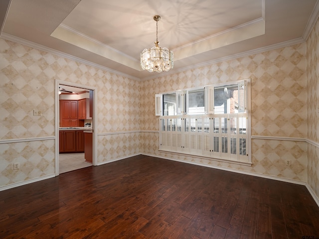 spare room featuring an inviting chandelier, a tray ceiling, crown molding, and light hardwood / wood-style flooring