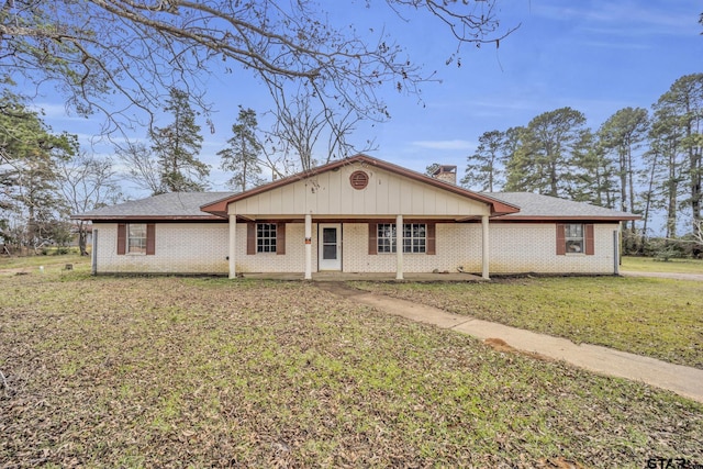 ranch-style home with a front yard, brick siding, roof with shingles, and a chimney