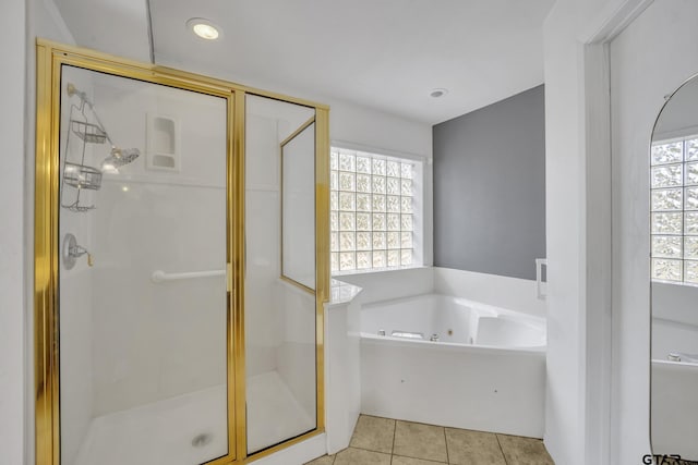 bathroom featuring tile patterned floors, plenty of natural light, a tub with jets, and a shower stall