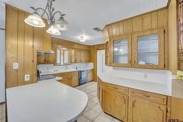 kitchen featuring visible vents, under cabinet range hood, light countertops, dishwashing machine, and range