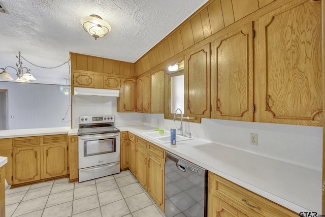 kitchen featuring under cabinet range hood, stainless steel appliances, light countertops, and a sink