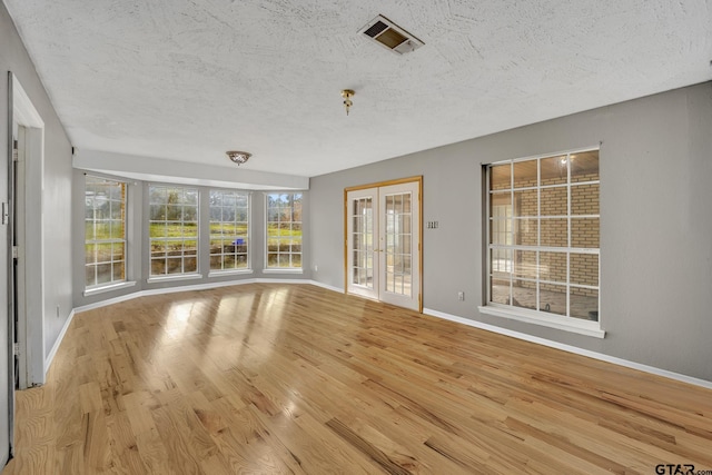 interior space featuring visible vents, baseboards, french doors, wood finished floors, and a textured ceiling