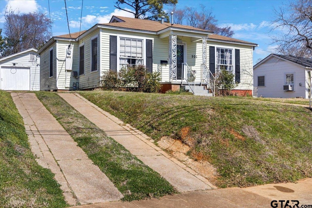 bungalow featuring a front yard, cooling unit, and an outbuilding