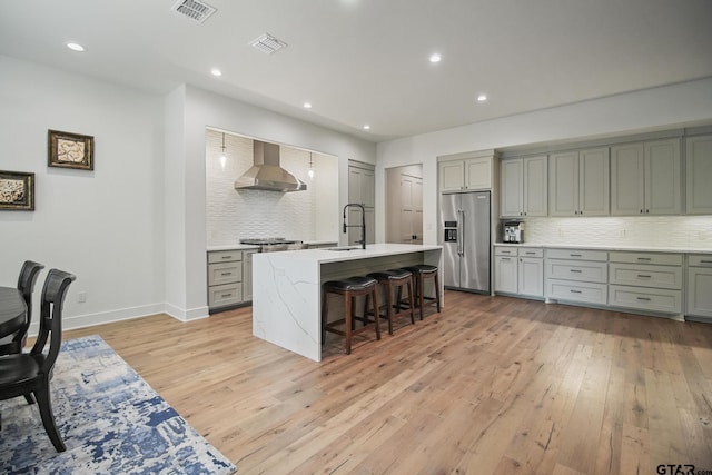 7863 Cross Rd, Tyler, TX 75703 - kitchen with high end refrigerator, wall chimney exhaust hood, gray cabinetry, tasteful backsplash, and recessed lighting