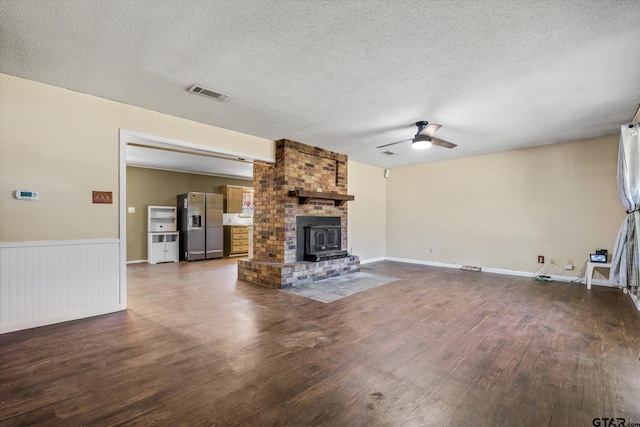 unfurnished living room with a textured ceiling, a wood stove, and dark hardwood / wood-style flooring