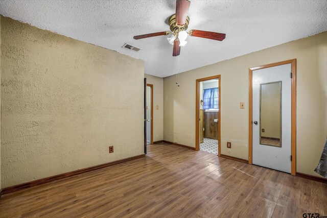 unfurnished room featuring ceiling fan, wood-type flooring, and a textured ceiling