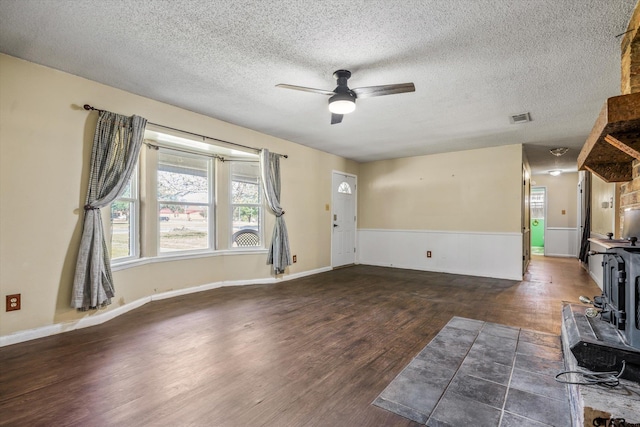 unfurnished living room featuring dark hardwood / wood-style flooring, a textured ceiling, and ceiling fan