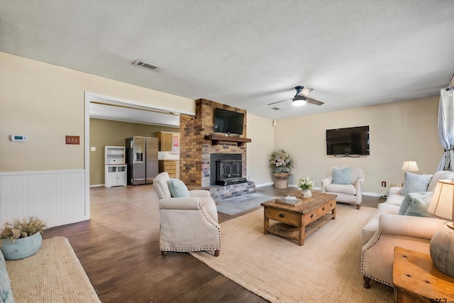 living room featuring a wood stove, hardwood / wood-style flooring, and ceiling fan