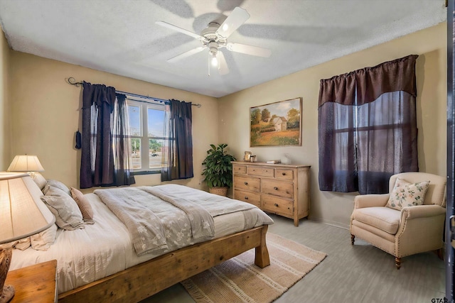 bedroom with a textured ceiling, light colored carpet, and ceiling fan