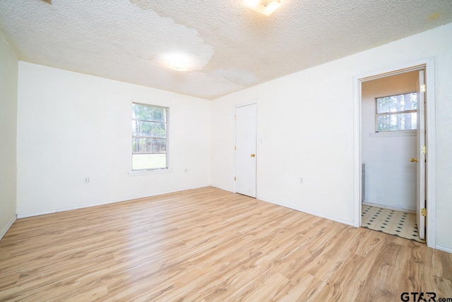 spare room featuring light wood-type flooring and a textured ceiling