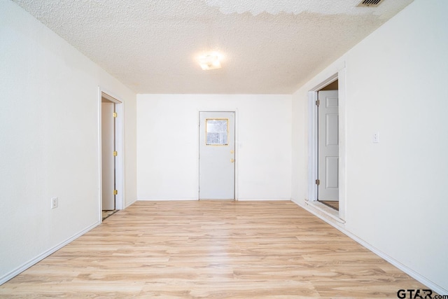 spare room featuring a textured ceiling and light hardwood / wood-style floors