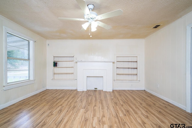 unfurnished living room featuring ceiling fan, light hardwood / wood-style floors, and a textured ceiling